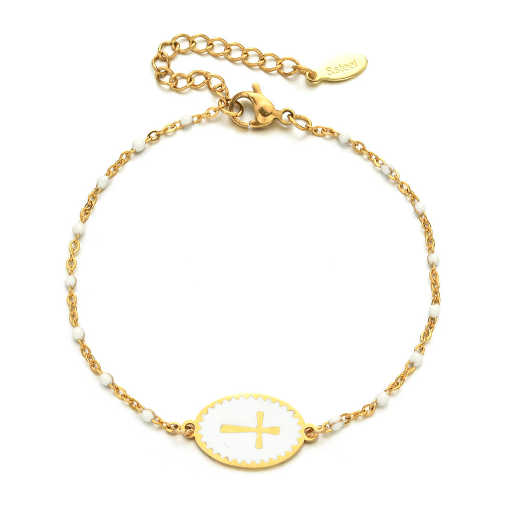 Gold bracelet with a cross charm on a white background