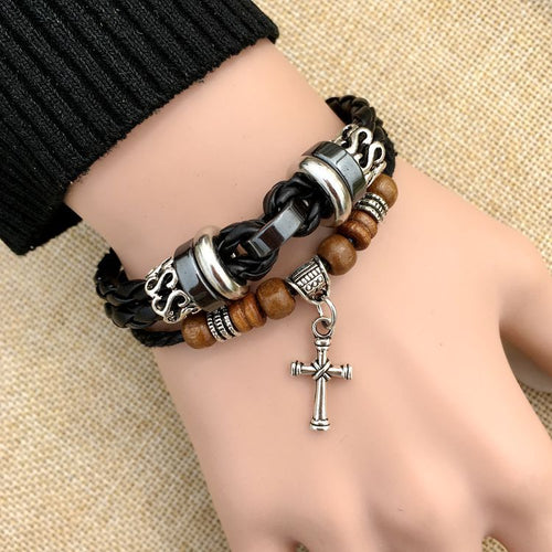 Multistrand bracelet with wooden beads and cross charm on a wrist against a beige background