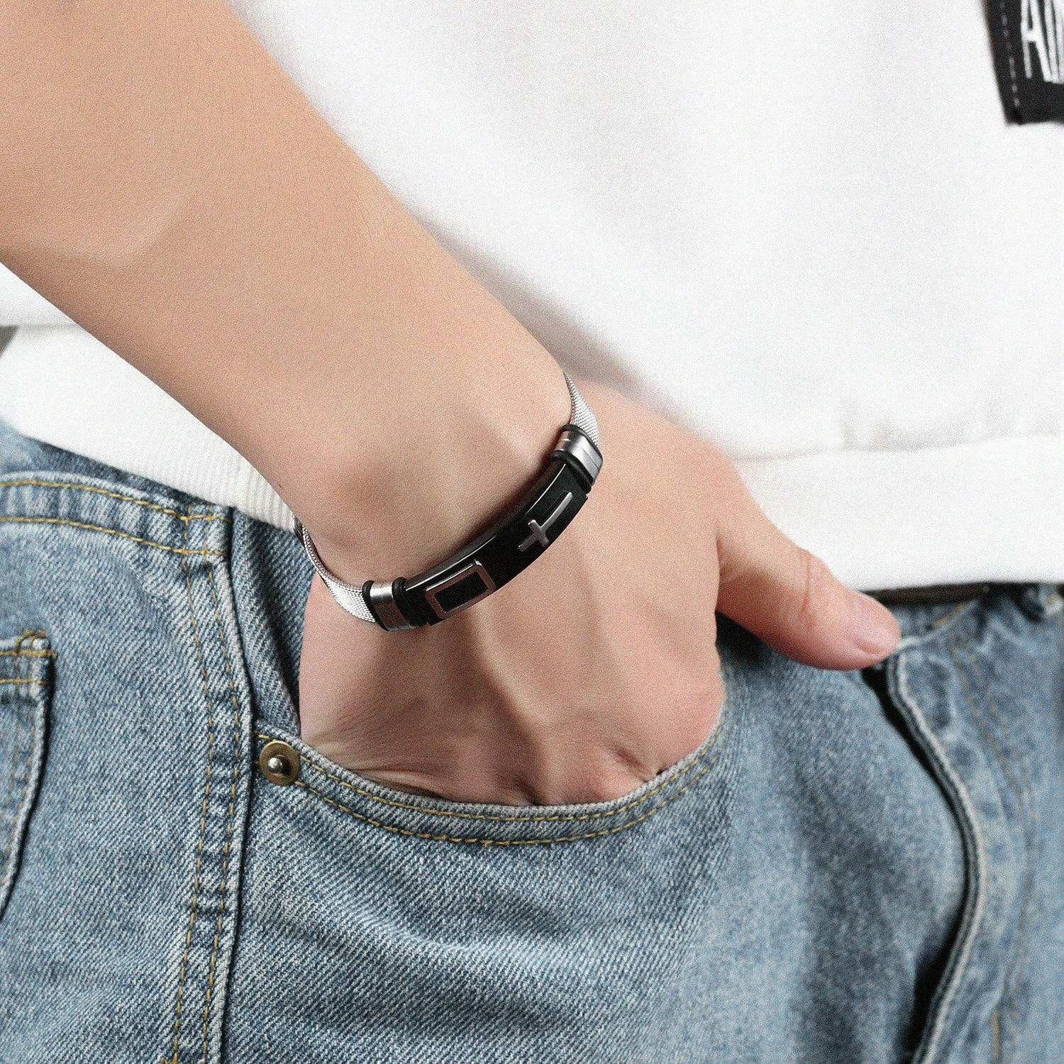 Person wearing a black and silver bracelet on a white background