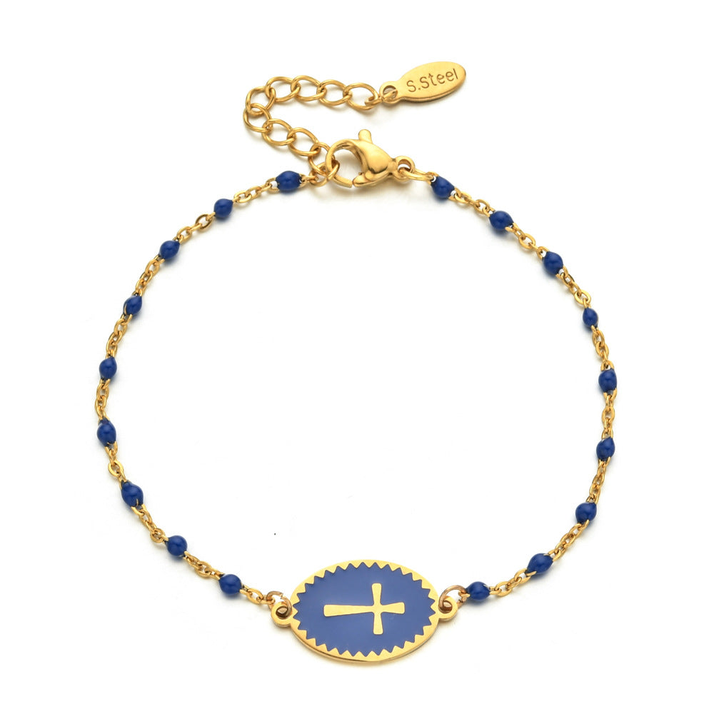 Gold bracelet with blue beads and a gold cross on a white background