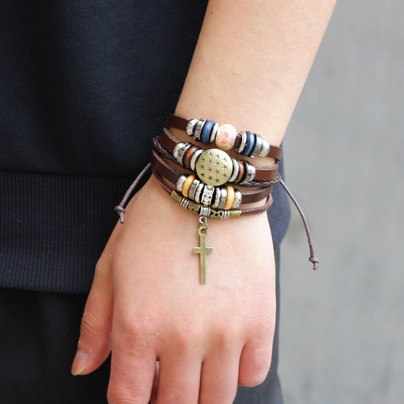 Multi-layered bracelet with beads and a cross charm on a wrist against a neutral background