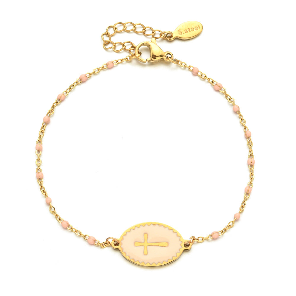 Gold bracelet with a cross charm on a white background