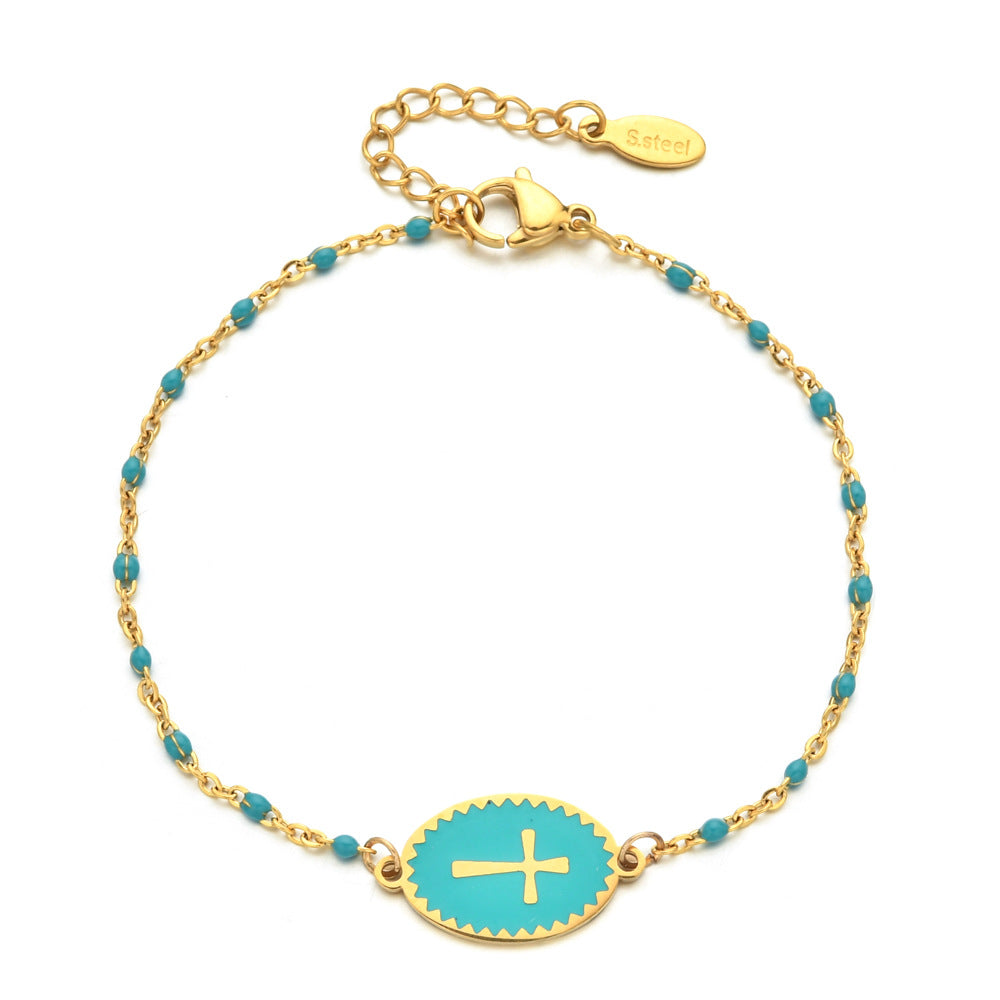 Gold bracelet with turquoise beads and a gold cross on a white background