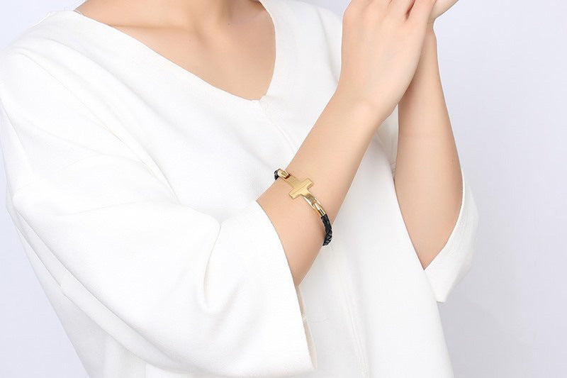 Person wearing a gold bracelet on a plain background