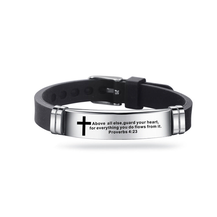 Black leather bracelet with silver tag featuring a cross and text on a white background