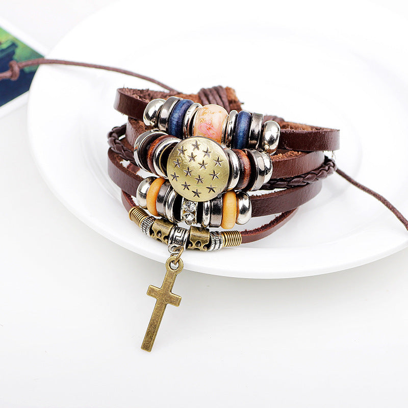 Multistrand leather bracelet with beads and a cross charm on a white surface