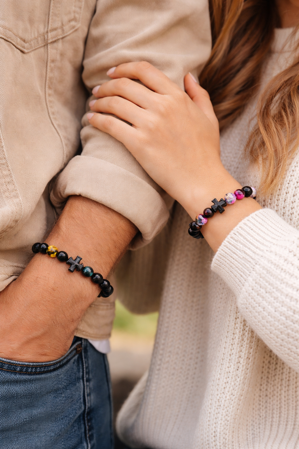 Two people holding hands with beaded bracelets on a blurred background